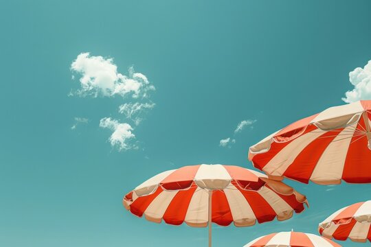 Three red and white striped umbrellas are set up in the sun