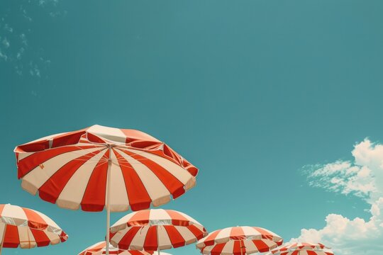 A row of red and white umbrellas are set up on a beach - Powered by Adobe