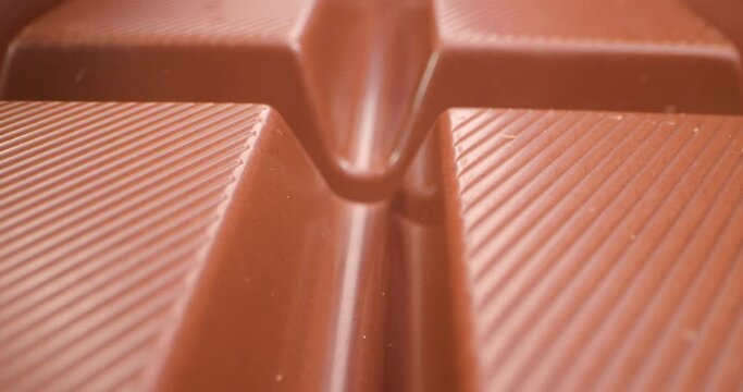 A close detailed view of the intricate ridges on a smooth and delicious brown chocolate bar, invoking a craving 