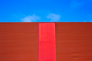 Nave industrial con fachada roja y cielo azul