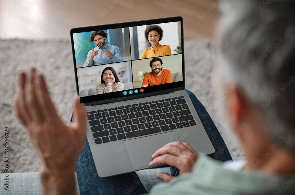 Poster elderly man sits on a couch, using a laptop to participate in a group video chat. the laptop screen 