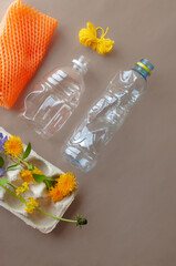 Egg carton, plastic bottle, fruit wrap and flowers on brown paper flat lay