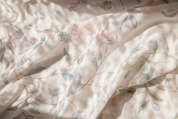 background with white farbic with flowers pattern in sunlight