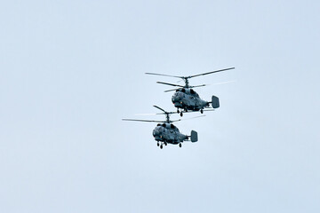 Two Russian military helicopters armed with missiles flies in blue sky, airborne mission of...