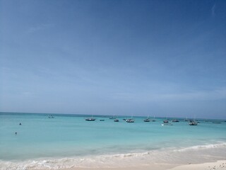 Boats on the horizon on the sea under a blue cloudy sky