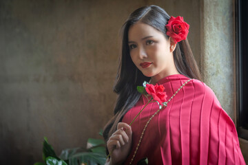 Beautiful portrait of an Asian female. A pretty woman wearing a red sash and green loincloth a traditional Thai dress costume. Asian tourists dress to blend in ancient Thai culture.