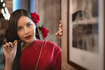 Beautiful portrait of an Asian female. A pretty woman wearing a red sash and green loincloth a traditional Thai dress costume. Asian tourists dress to blend in ancient Thai culture.