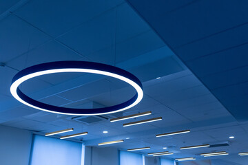 Lighting equipment. Large round fluorescent lamp and many linear LED lamps on the suspended...
