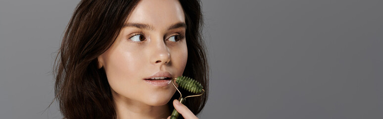 A woman applies a jade roller to her face, showcasing a glowing, healthy complexion. © LIGHTFIELD STUDIOS