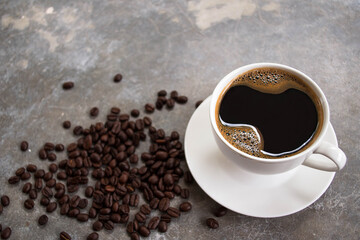 Black coffee in a white glass placed on an old cement table with coffee beans.