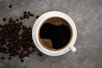 Top view black coffee in a white glass placed on an old cement table with coffee beans.
