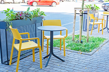street cafe with wicker furniture and fresh red flowers. Daily Lifestyle.trash in a black trash bag on the street. Everyday waste