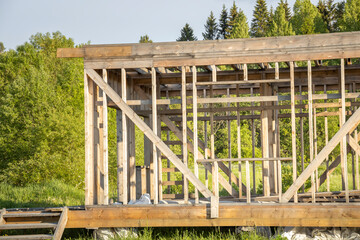 A wooden structure with a slanted roof is being built in a field