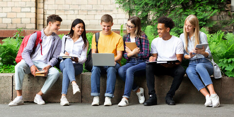 Fototapeta premium Education concept. Happy teens preparing for exams in university campus with books and laptop
