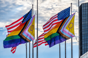 American flags and LGBTQ rainbow flags flying together in the wind, Detroit, USA