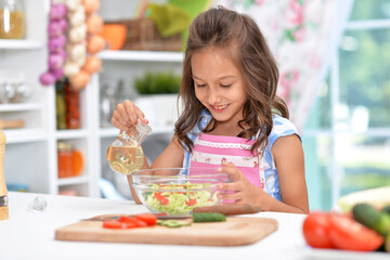 Cute happy girl coocking salad on kitchen