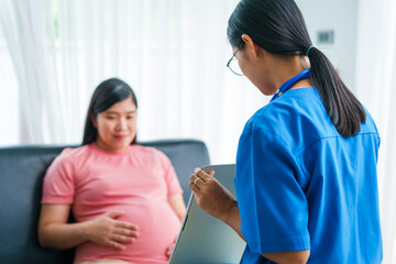 Asian female doctor and nurse perform an ultrasound on a pregnant woman, using a stethoscope and...