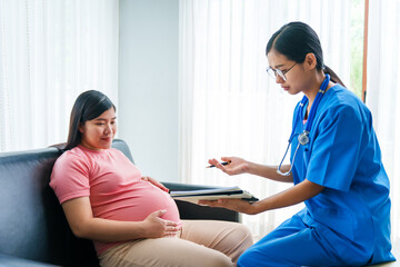 Asian female doctor and nurse perform an ultrasound on a pregnant woman, using a stethoscope and medical equipment, ensuring her health and preparing for a successful birth.