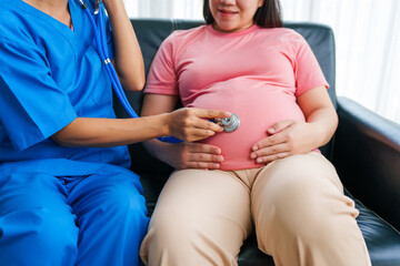 Asian female doctor and nurse perform an ultrasound on a pregnant woman, using a stethoscope and...