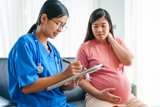 Asian female doctor and nurse consult on sofa with a pregnant woman, using ultrasound and stethoscope, addressing illnesses morning sickness, gestational diabetes, hypertension, ensuring her health.