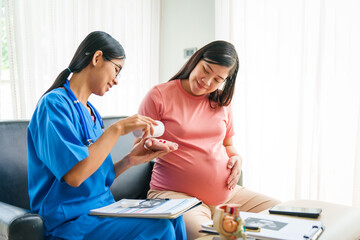 Asian female doctor and nurse consult on sofa with a pregnant woman, using ultrasound and stethoscope, addressing illnesses morning sickness, gestational diabetes, hypertension, ensuring her health.