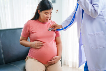 Asian female doctor nurse encouragement to a pregnant woman on a sofa, using ultrasound and...