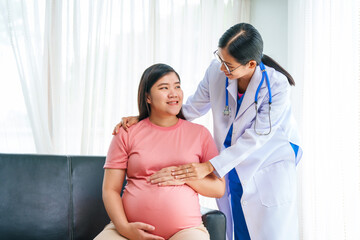 Asian female doctor nurse encouragement to a pregnant woman on a sofa, using ultrasound and...