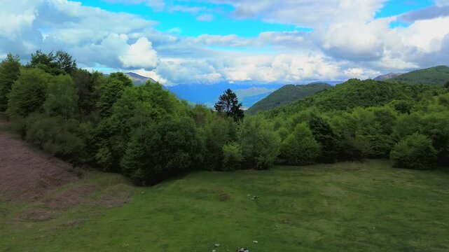 Aerial view of the Alpine mountain peaks on the border of Italy and Switzerland. The drone flies between green slopes and dramatic clouds. Trekking and tourism in the mountains. Green Paneth. Oxygen. 