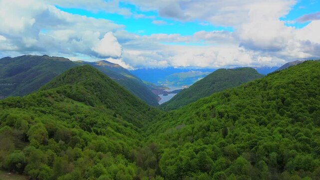 Aerial view of the Alpine mountain peaks on the border of Italy and Switzerland. The drone flies between green slopes and dramatic clouds. Trekking and tourism in the mountains. Green Paneth. Oxygen. 