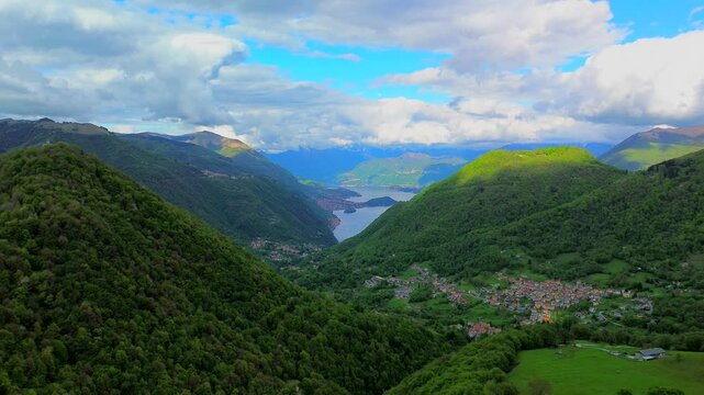 Aerial view of the Alpine mountain peaks on the border of Italy and Switzerland. The drone flies between green slopes and dramatic clouds. Trekking and tourism in the mountains. Green Paneth. Oxygen. 