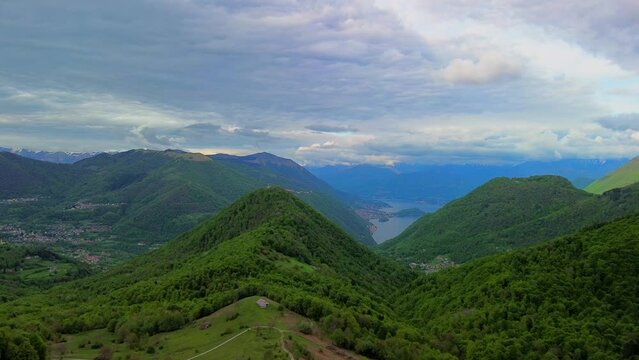 Aerial view of the Alpine mountain peaks on the border of Italy and Switzerland. The drone flies between green slopes and dramatic clouds. Trekking and tourism in the mountains. Green Paneth. Oxygen. 