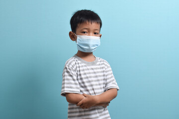 Asian Boy wearing health mask isolated on blue background. Medical and health concept. Human population viruses, infections, flu disease prevention