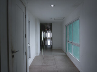 Dimly lit corridor inside the hotel to enter the rooms, with light streaming in through the windows.