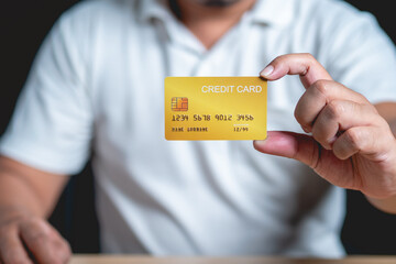 A man in a white shirt is holding a credit card.