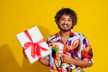 Photo portrait of pretty young guy hold point gift shopping wear trendy colorful outfit isolated on yellow color background