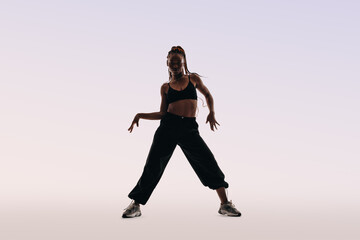 Portrait of a young woman dancing with energetic moves in a studio