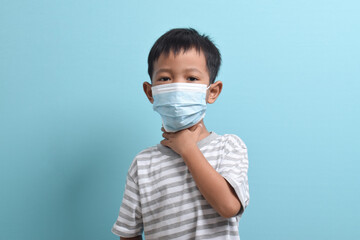 Asian Boy wearing health mask isolated on blue background. Medical and health concept. Human population viruses, infections, flu disease prevention