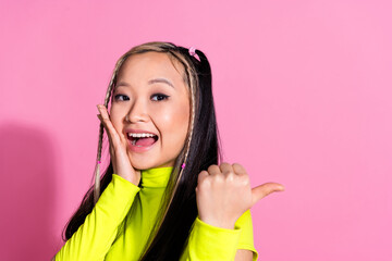 Photo of impressed girl with dyed hairdo dressed yellow turtleneck directing at discount empty space isolated on pink color background