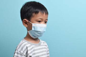 Asian Boy wearing health mask isolated on blue background. Medical and health concept. Human population viruses, infections, flu disease prevention