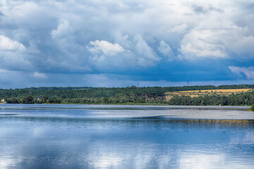 Summer landscape with river, village, blue sky and clouds