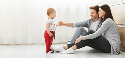 A young family is playing together in their living room. A man and a woman are sitting on the...
