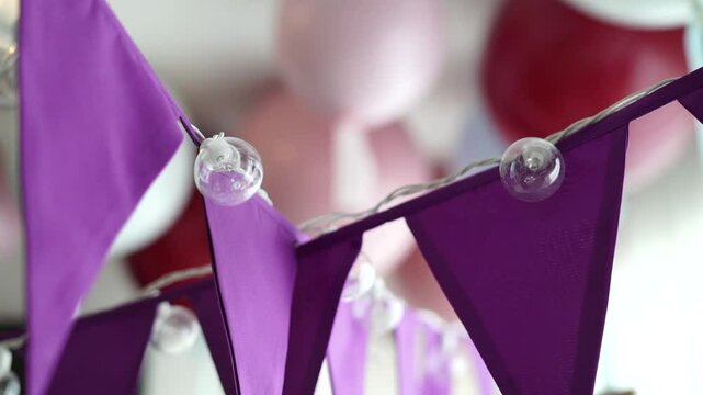 decoraci&oacute;n con banderines morados y globos rosados en una fiesta infantil