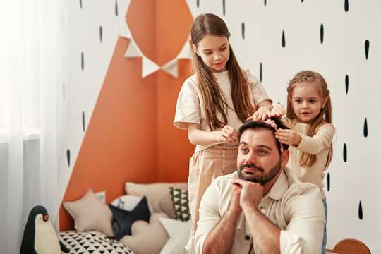 Father creating loving memories with daughters at home in a playful and affectionate environment