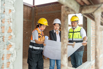 Female architect, Male engineering and Female construction looking at blueprint in house under construction. Construction concept of engineering working on site teamwork.