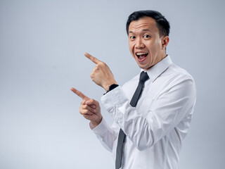 Asian man in a white dress shirt and black tie, confidently pointing to his left with a slight smile. The background is plain, keeping the focus on his gesture and expression