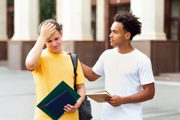 Failed test. Teenage guy consoling friend over bad exam result outdoors