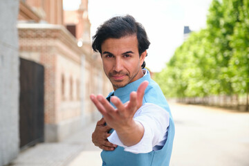 Portrait of a stylish Indian man wearing a traditional Indian vest stretching out his hand inviting to dance with him