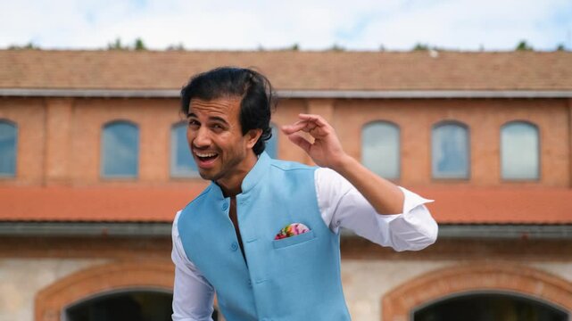 Young indian man dancing in the street wearing colorful clothes