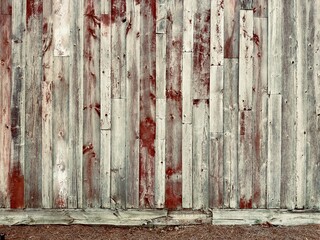 A rustic, weathered red wood barn wall exudes timeless charm, with its aged, textured planks and faded paint, capturing the essence of rural heritage and pastoral beauty.
