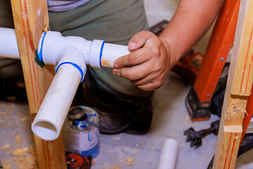 Plumber technician applying glue to join PVC pipes
